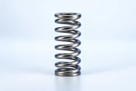 Upright helical compression spring with spaced coils and flat ends resting on a surface.