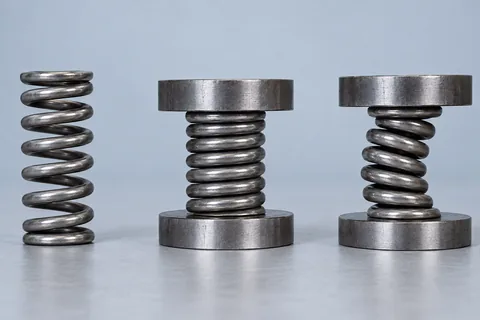 Three matching springs: free, compressed straight, and compressed with lateral buckling.